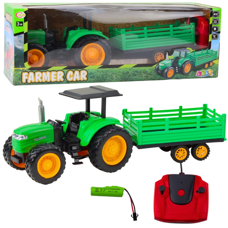 Zelený zdalně řízený farmářský traktor s přívěsem